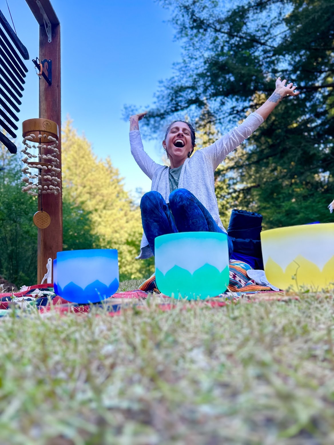 Eireann, founder of Lotus Flow Health, smiling outdoors among sound healing bowls in Santa Cruz